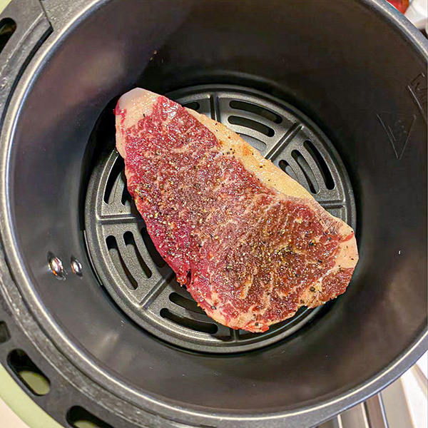 Seasoned steak in the air fryer basket