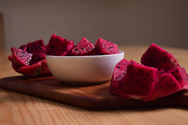 Bowl of cubed red dragon fruit on wood