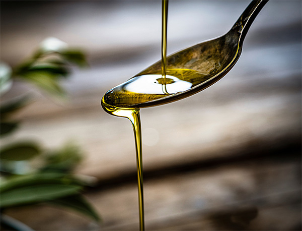 Extra Virgin Olive Oil drizzling from a spoon