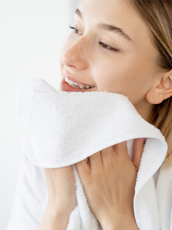 Woman drying her face with a white towel