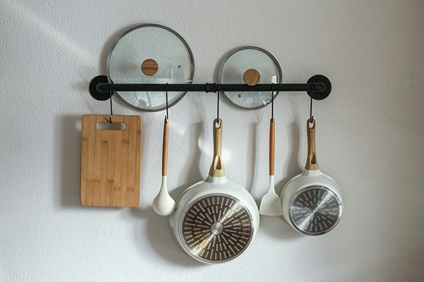 Ceramic cookware and other kitchen utensils hanging on a wall rack